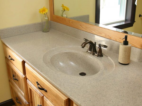 tan corian bathroom sink with wooden cabinets