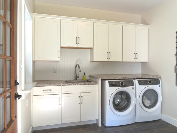 white kitchen cabinets in mudroom with marble sink