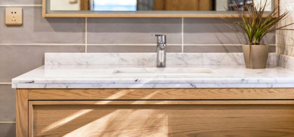 white and gray corian bathroom vanity top over brown cabinet